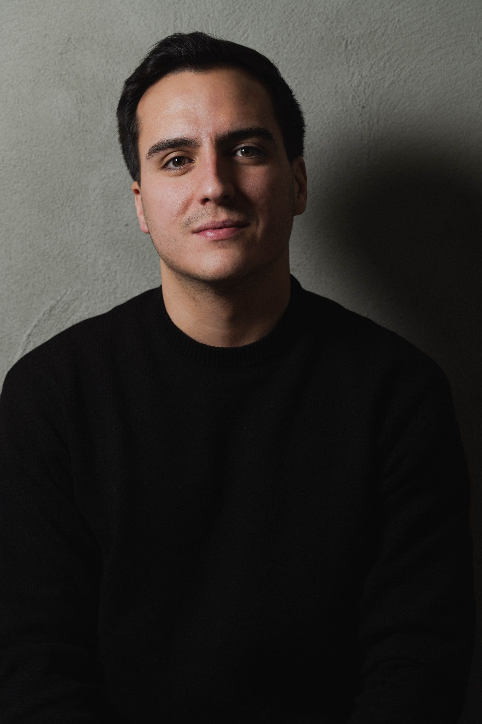Juan Miguel Hernández, retrato con jersey negro sobre pared gris